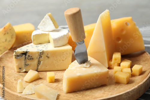 Different types of delicious cheese in wooden plate, closeup photo