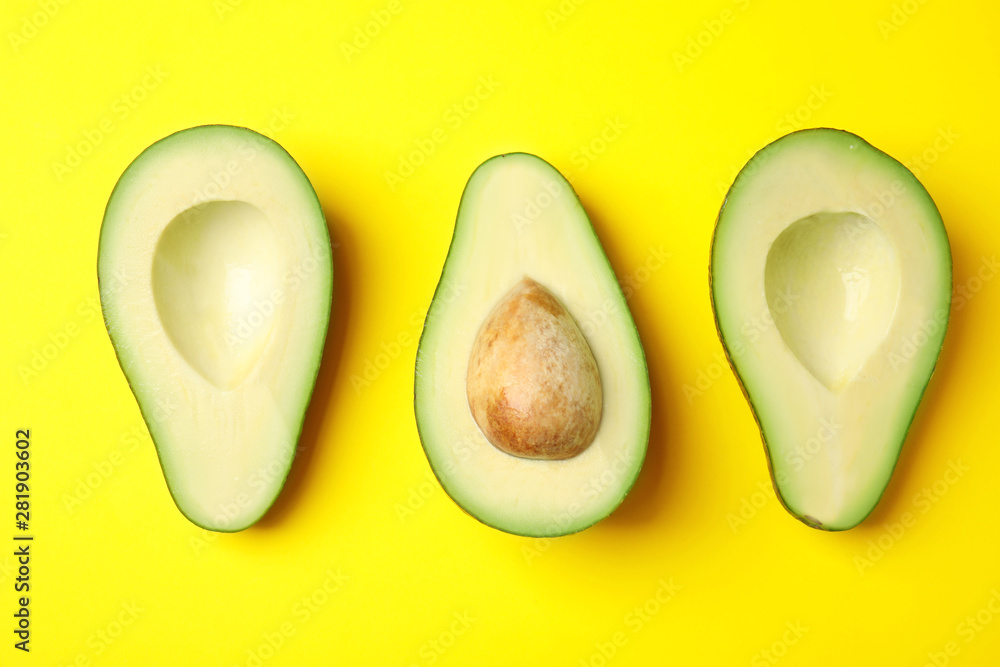 Naklejka premium Cut fresh ripe avocados on yellow background, flat lay