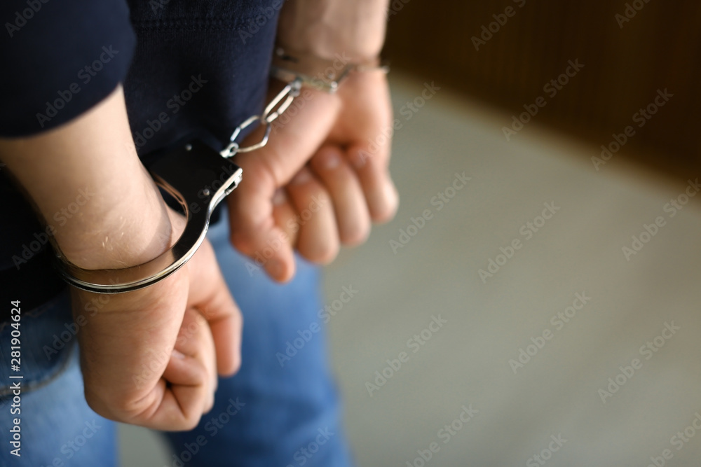 Man detained in handcuffs indoors, space for text. Criminal law - obrazy, fototapety, plakaty 