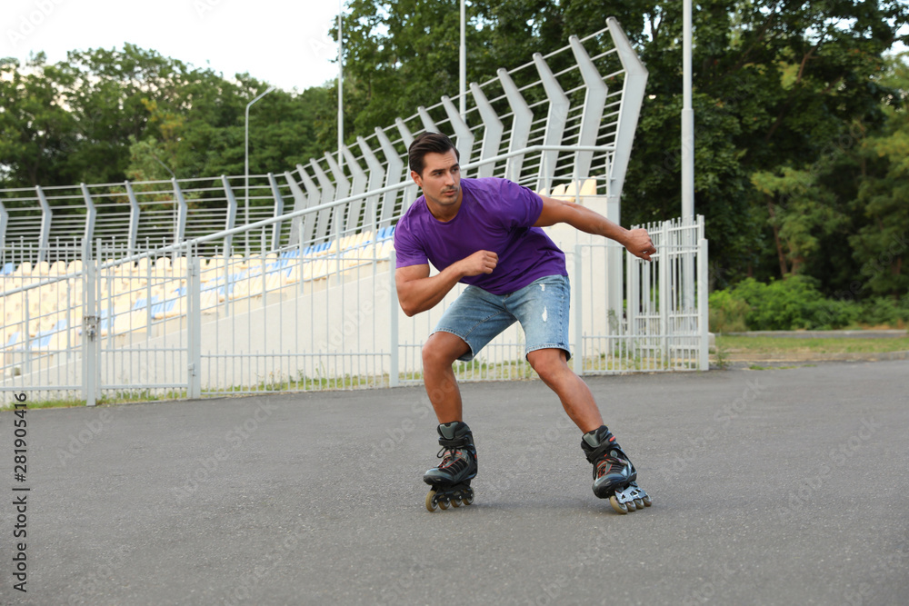 Fototapeta premium Handsome young man roller skating outdoors. Recreational activity