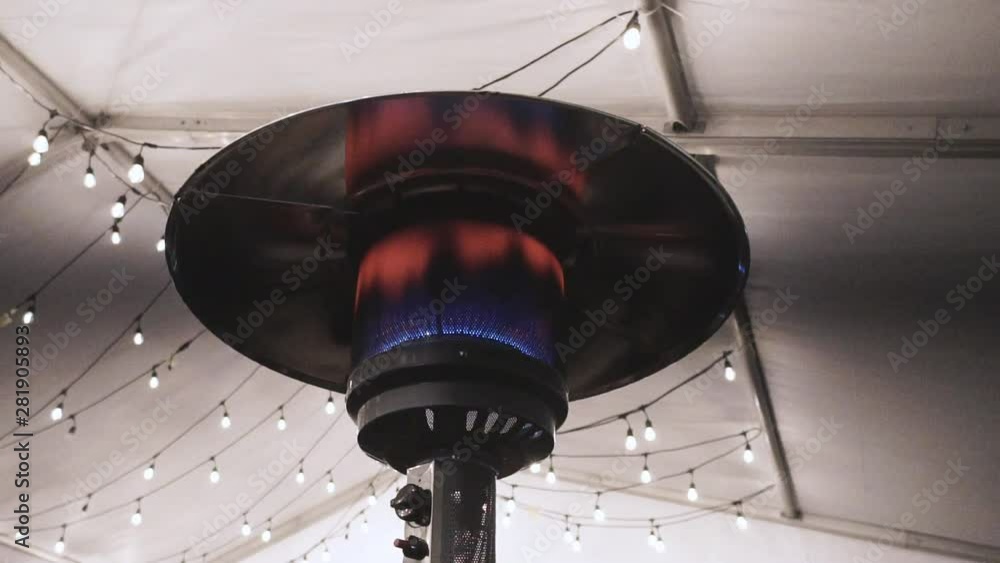 Warming artisan winter gas lamp fireplace or kerosene lamp outdoors, Decorative restaurant gas flame outdoor with led Christmas lights on the background.