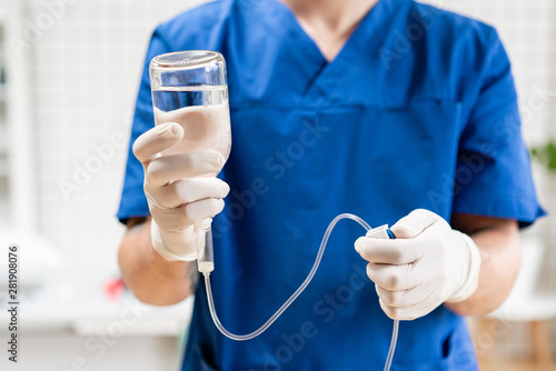 Doctor in blue uniform holding drip iv and infusion pump. Medical treatment emergency concept.. Intravenous fluid for seriously patient in the emergency room at hospital.