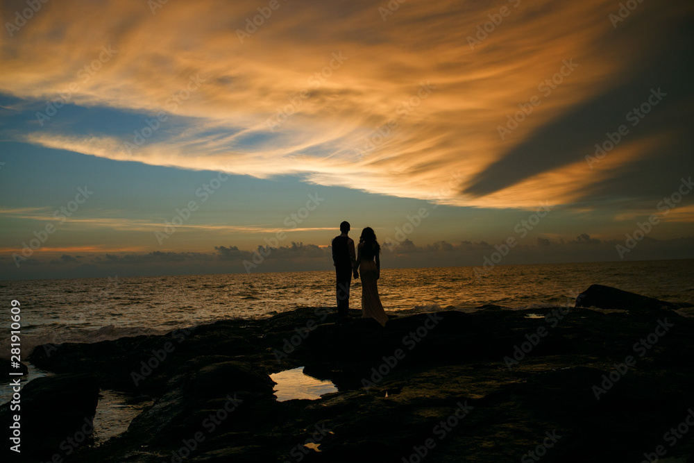 silhouette of couple on sunset beach, beautiful background about love and relationships, man and woman. Happy couple enjoying sunset on the sea cliff