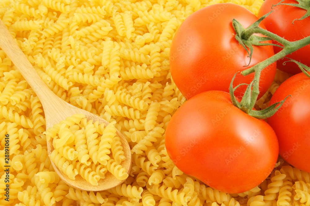 Macaroni background with wooden spoon and tomatoes