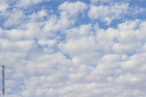 Airplane in the blue sky with white cumulus clouds