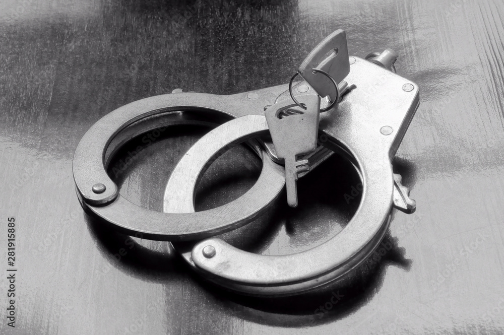 Obraz premium Steel metallic handcuffs with keys on wooden table