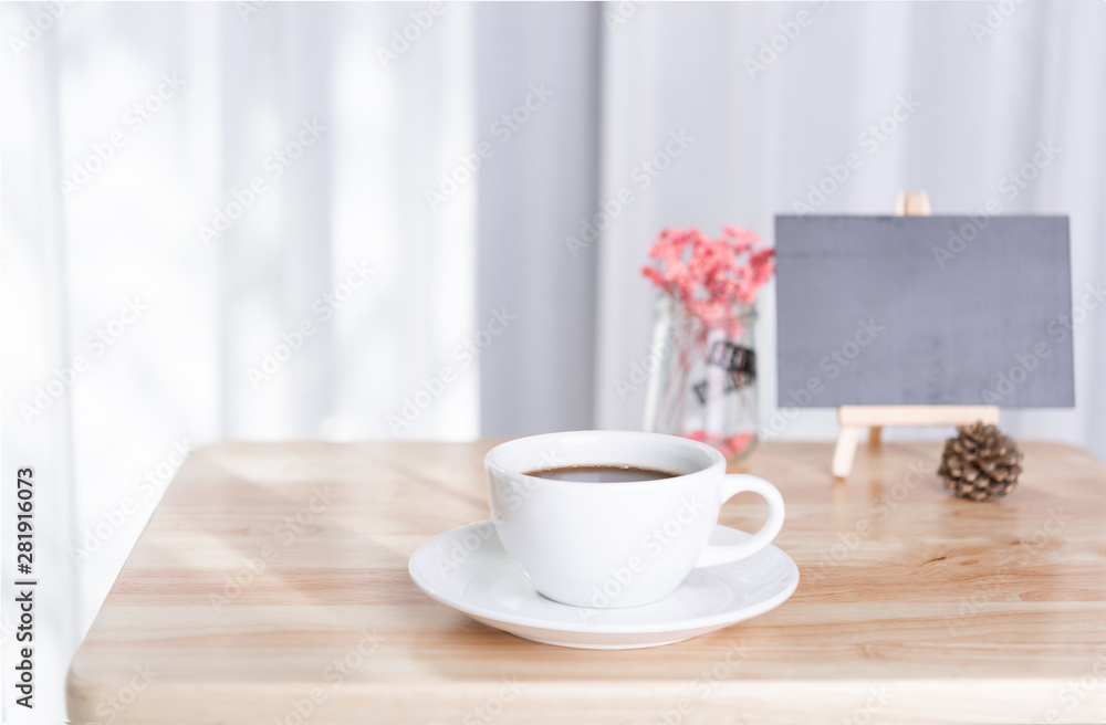 coffee cup and black board on office table with white curtain background in morning light coffee cup and black board on office table with white curtain background in morning light