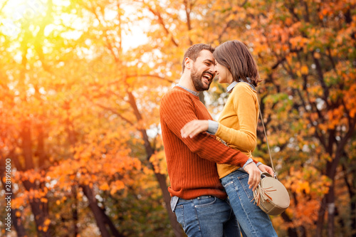 Young beautiful couple in love staying and kissing on the autumn park on sunset