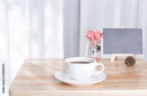 coffee cup and black board on office table with white curtain background in morning light