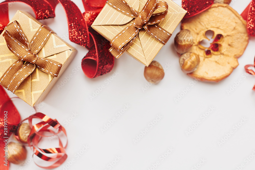 Christmas and New Year border composition. Gift boxes with red ribbon, hazelnuts and slice of dried apple over white background Christmas and New Year border composition. Gift boxes with red ribbon, hazelnuts and slice of dried apple over white background