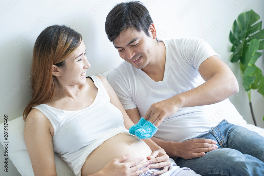 Pregnant couple of husband and wife feels love and relax at home. Young expecting holds baby in pregnant belly. Father take care of pregnant mother. Concept of maternity and pregnancy care. Pregnant couple of husband and wife feels love and relax at home. Young expecting holds baby in pregnant belly. Father take care of pregnant mother. Concept of maternity and pregnancy care.