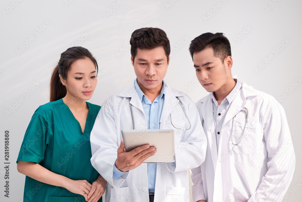 Medical team includes doctors and nurse looking at an ipad/tablet computer together Medical team includes doctors and nurse looking at an ipad/tablet computer together