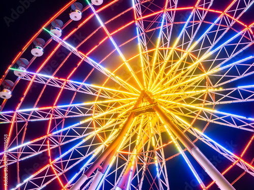 Large ferris wheel shining with yellow, blue and red colors at night