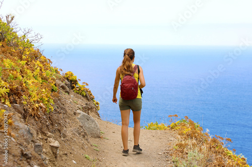 Young hiker woman walking on a trail overlooking the sea in Tenerife