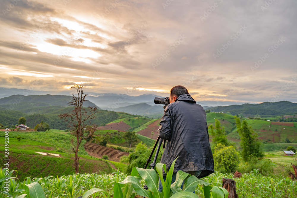 Fototapeta premium Travel photographer with views of the forest and rice fields, mountain, enjoying the beautiful surrounding nature in the cold rainy season.
