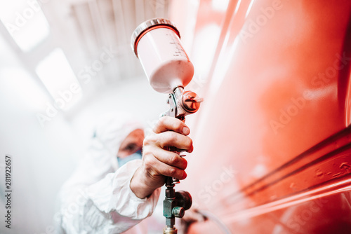 Fotografía close up of male holding spray gun and painting a car