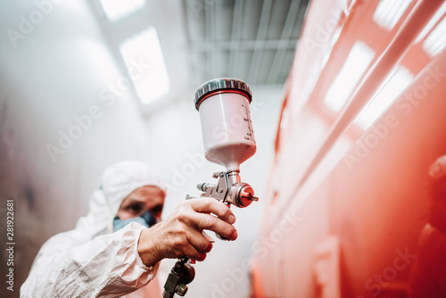 close up of paint spray gun, worker painting a car photo