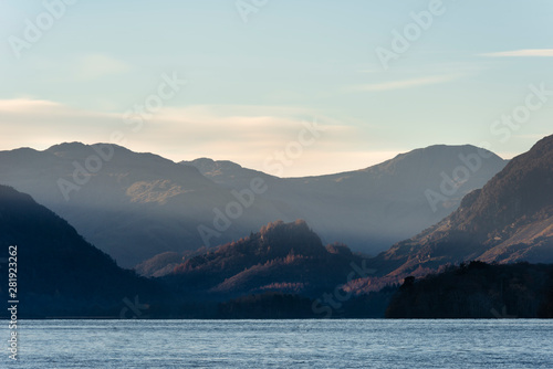 Stunning long exposure landscape image of Derwent Water in Lake District during Autumn Fall sunrise with soft pastel colors