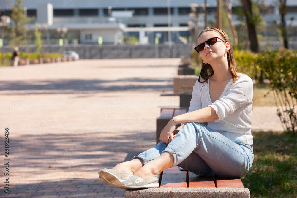 Young beautiful woman sitting on bench in park.