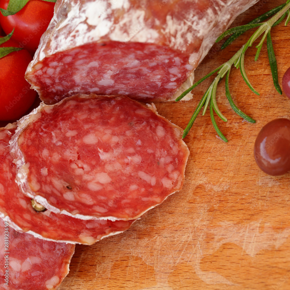 Gourmet food - salami, olives and rosemary herbs on wooden table Gourmet food - salami, olives and rosemary herbs on wooden table