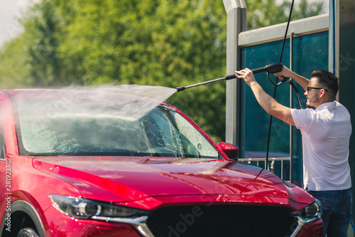 Manual car wash with pressurized water in car wash outside. Summer Car Washing. Cleaning Car Using High Pressure Water. Washing with soap. Close up concept.