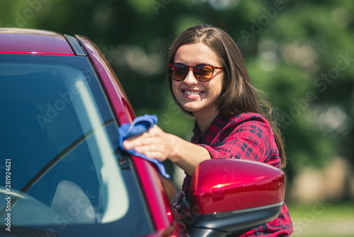 Car detailing - the female holds the microfiber in hand and polishes the car. Selective focus. Girl cleaning red car 2018