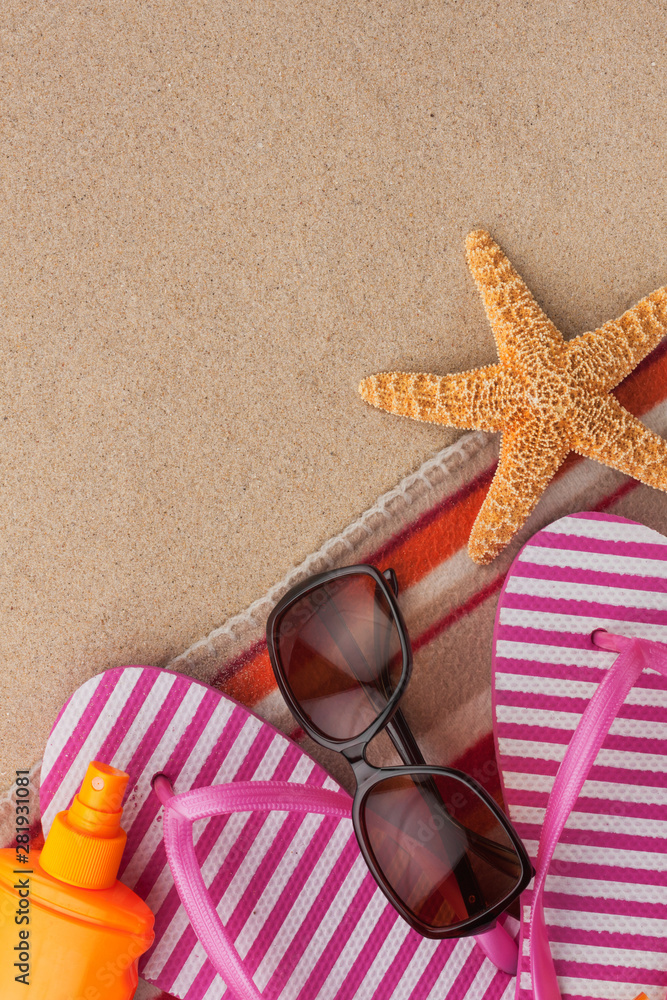 Summer accessories flip flops and towel. Sand beach texture background.