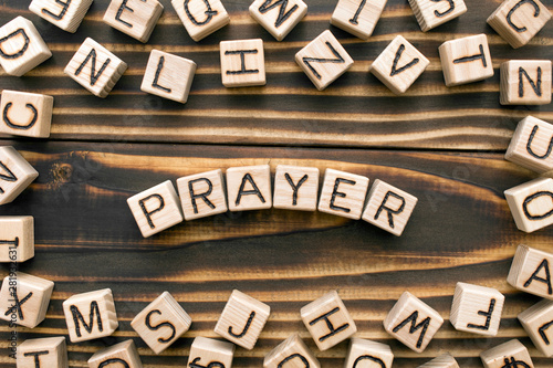 Prayer - word from wooden blocks with letters, speaking to God concept, random letters around, top view on wooden background