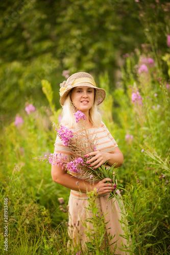 Cute smiling blonde woman with wildflowers. Summer portrait of a woman with rose-tea in the field.