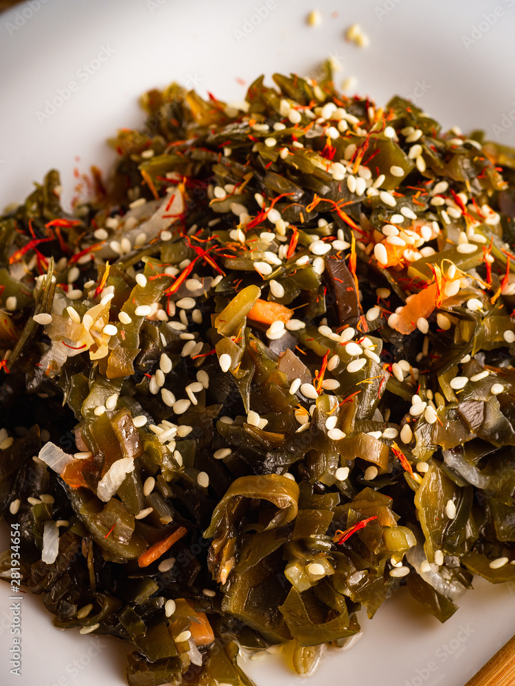 Seaweed salad with sesame seeds is on a white plate