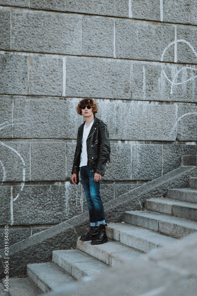 Calm young rocker on stone stairs standing alone Calm young rocker on stone stairs standing alone