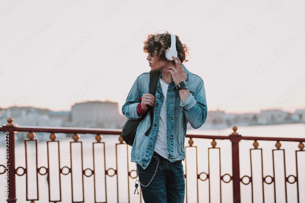 Serious man with headphones is walking outdoors