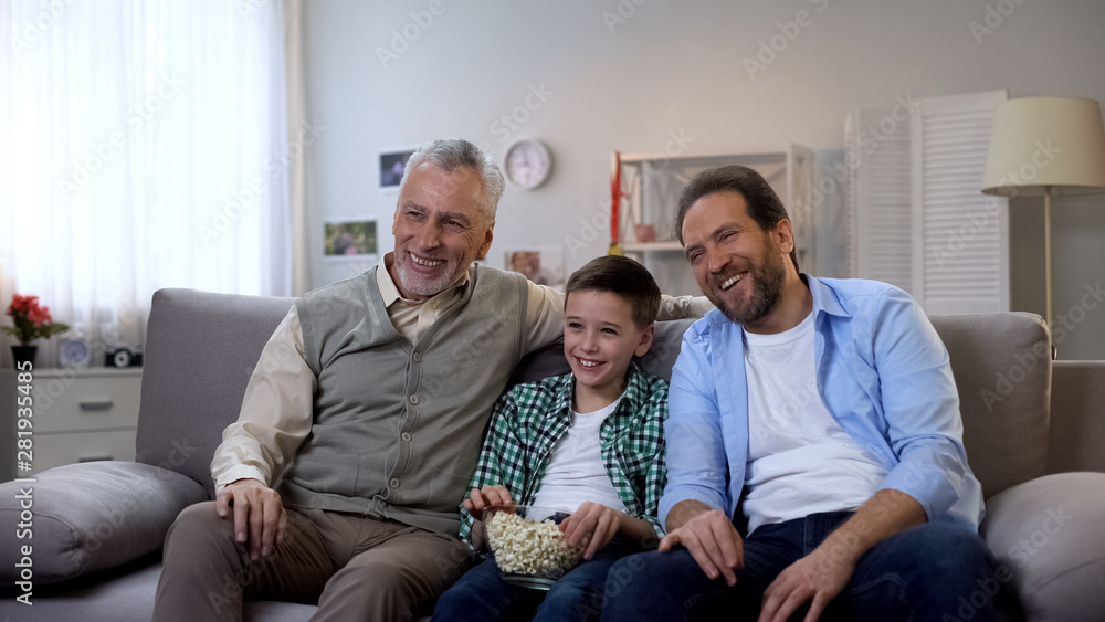 Joyful grandpa, father and son enjoying comedy show on tv, having fun together Joyful grandpa, father and son enjoying comedy show on tv, having fun together