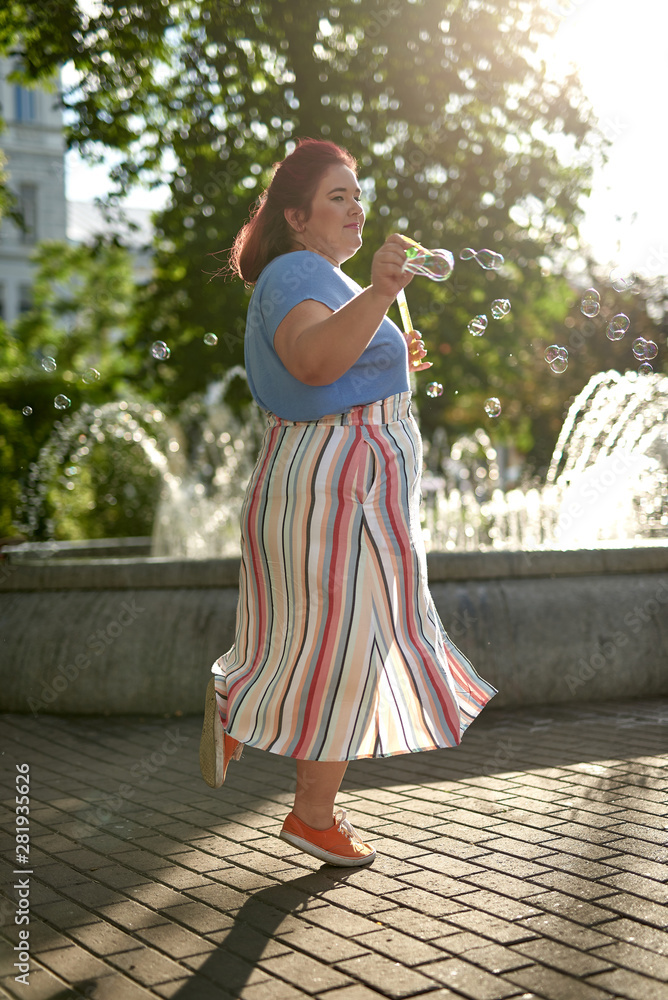 Fototapeta premium Fat and young woman with bubble soap jar in the city