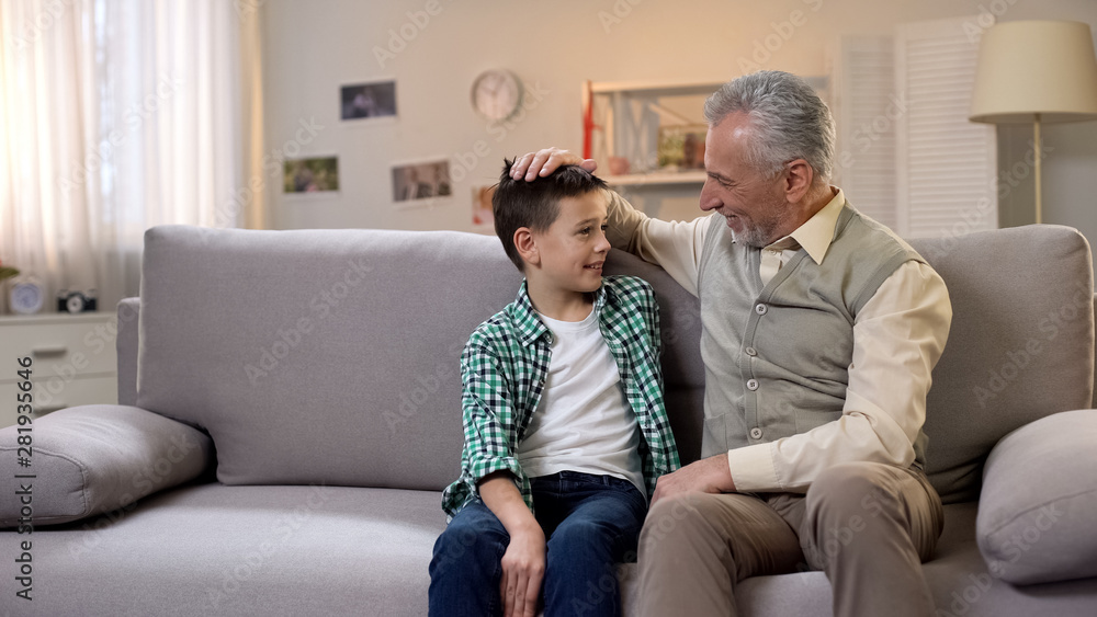 Mature granddad stroking head of preteen grandson, love and care, family