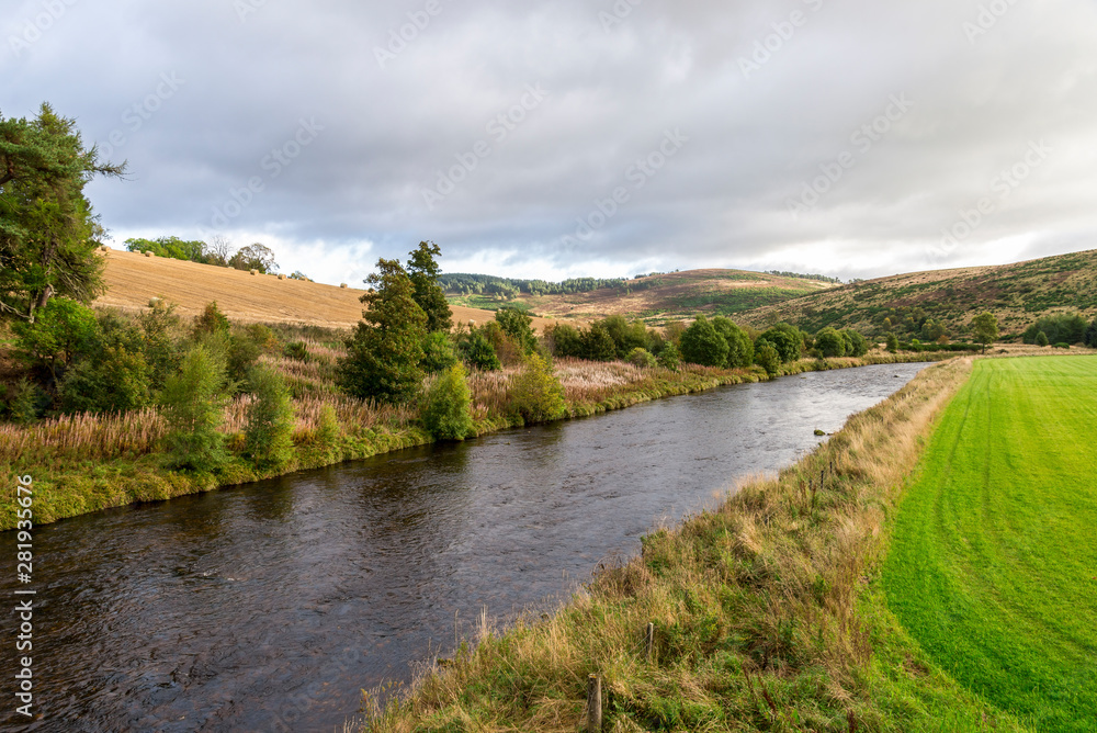 A scenic autumn view of the flowing river and low hillside in Cairngorms National Park