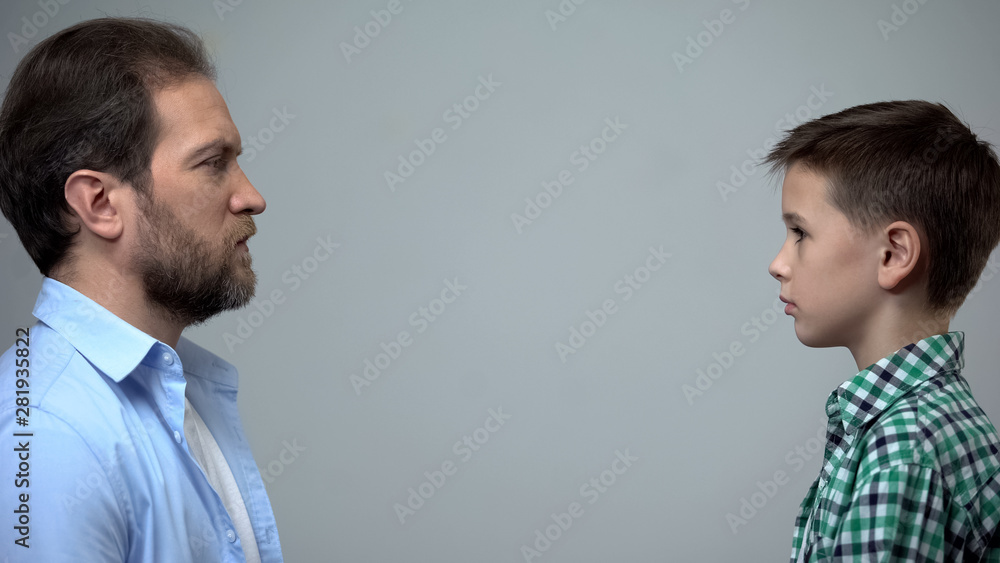 Serious father looking at little son, child upbringing, adoption and social care Serious father looking at little son, child upbringing, adoption and social care