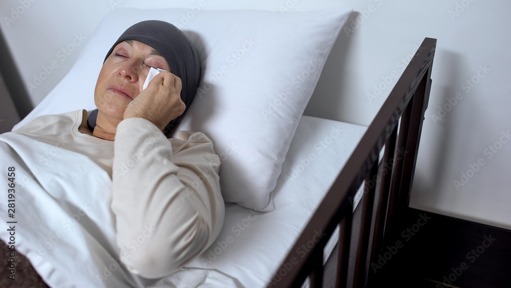 Female patient crying in hospital bed, wiping tears with handkerchief, cancer Female patient crying in hospital bed, wiping tears with handkerchief, cancer