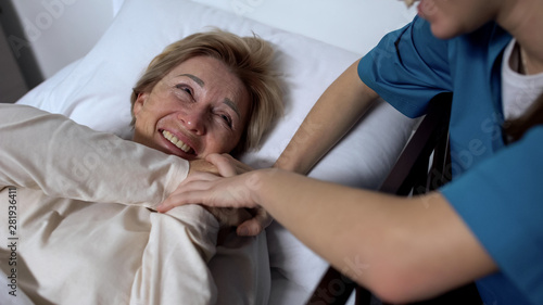 Cheerful patient laughing at jokes of nurse, lying in sickbed, positive mood