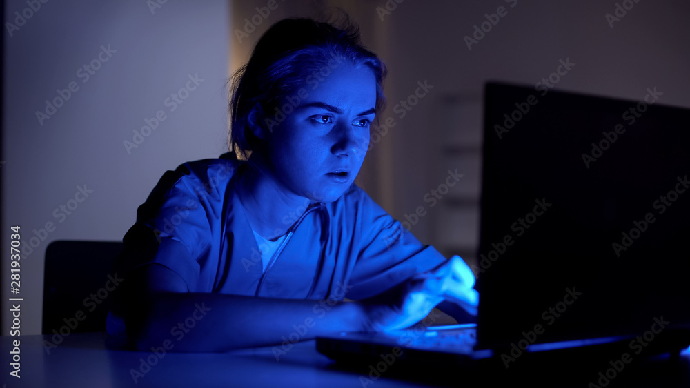 Nurse on duty typing on laptop, hurrying to meet deadline at work, night shift Nurse on duty typing on laptop, hurrying to meet deadline at work, night shift