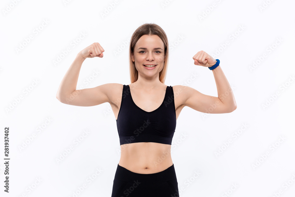 Young sporty blond woman in a black sportswear showing biceps standing over white background. Young sporty blond woman in a black sportswear showing biceps standing over white background.