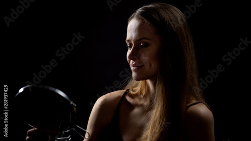 Smiling female looking at mirror reflection against black background, beauty