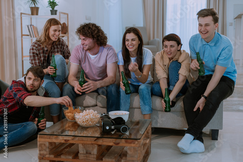 Portrait of a very charismatic people cheers with beer bottles in front of the tv while watching the football match very excited waiting to see all match tv photo