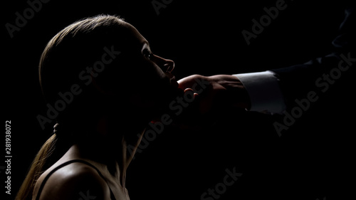 Cruel man holding and looking at beautiful face of young lady, human trafficking