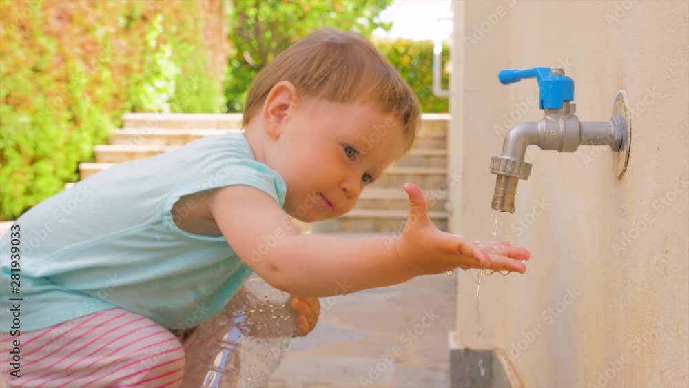No water flowing from the tap. Baby girl checking water flow from tap