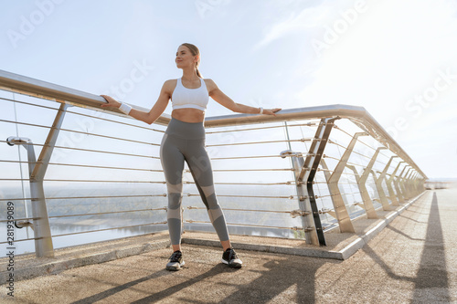 Young athletic lady in sport wear on foot bridge