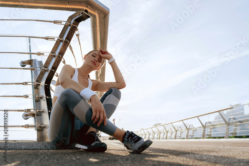 Sportive lady sitting on foot bridge ground © Yakobchuk Olena