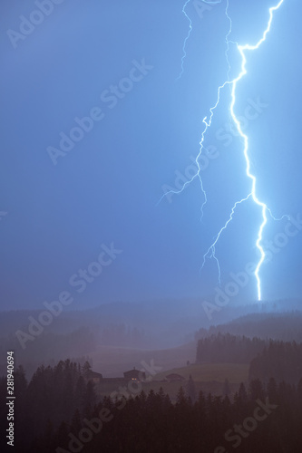 Lightning thunder storm over the cottage at summer night in Austria alps.