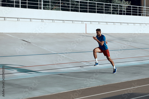 Sportive man training and running on stadium