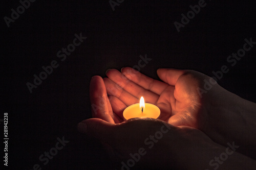 round candle in female hands, light in hands, festive theme